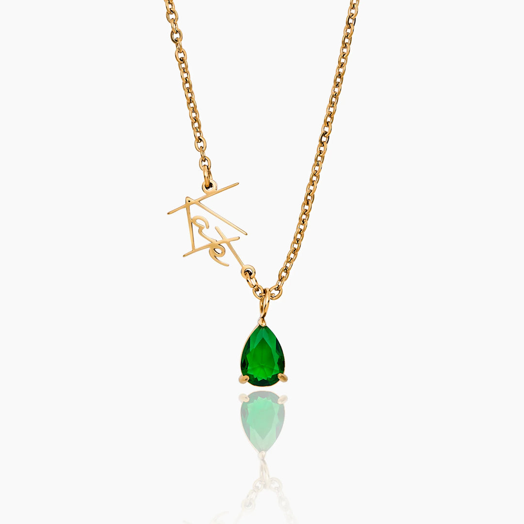 Gold necklace with a green teardrop pendant on a white background
